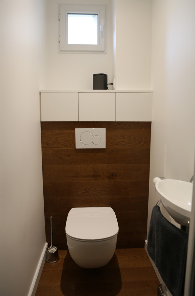 Design ideas for a medium sized contemporary cloakroom in Other with beaded cabinets, white cabinets, a wall mounted toilet, dark hardwood flooring and a wall-mounted sink.