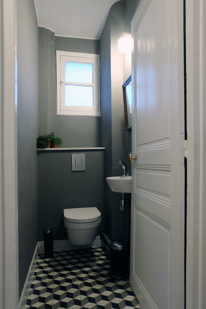 Idéer för små funkis toaletter, med en vägghängd toalettstol, grå väggar, ett väggmonterat handfat, cementgolv och flerfärgad kakel