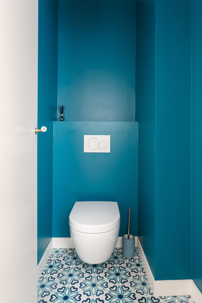 Kleine Moderne Gästetoilette mit blauen Schränken, Wandtoilette, blauen Fliesen, blauer Wandfarbe, Zementfliesen für Boden, blauem Boden und weißer Waschtischplatte in Paris