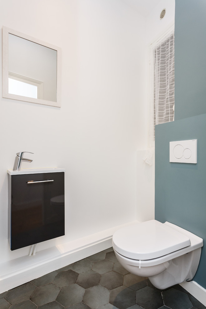 Aménagement d'un petit WC suspendu scandinave avec un placard à porte plane, des portes de placard noires, un mur blanc, un sol en carrelage de céramique, un lavabo posé, un plan de toilette en surface solide, un sol gris et un plan de toilette blanc.