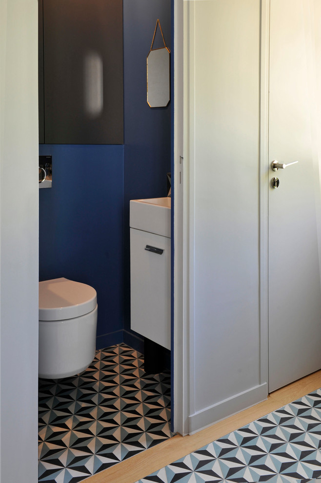Kleine Moderne Gästetoilette mit Kassettenfronten, weißen Schränken, Wandtoilette, blauer Wandfarbe, Vinylboden, Wandwaschbecken, blauem Boden und weißer Waschtischplatte in Sonstige