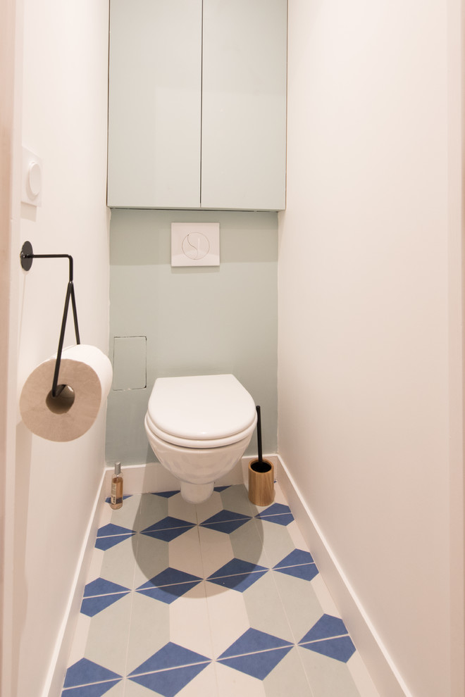 Foto på ett stort funkis toalett, med en vägghängd toalettstol, gröna väggar, cementgolv och blått golv