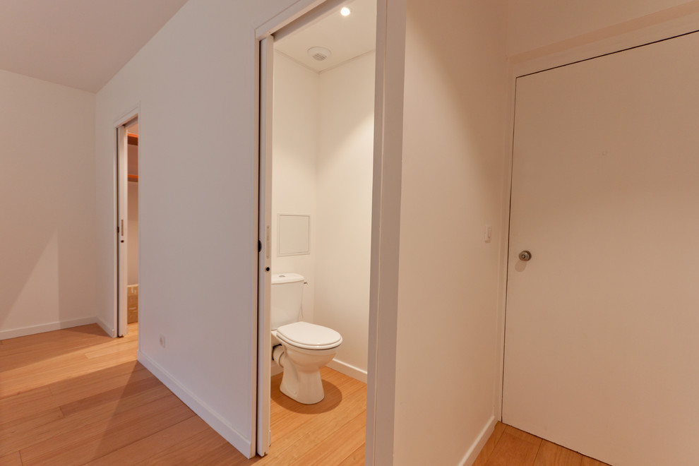 Cette photo montre un petit WC et toilettes chic avec WC à poser, un mur blanc et parquet clair.