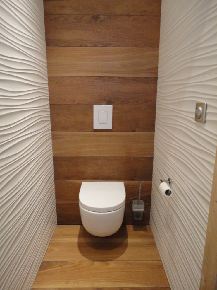 Idéer för små funkis toaletter, med en vägghängd toalettstol, flerfärgade väggar och mellanmörkt trägolv
