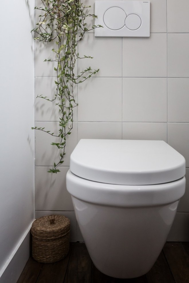 Inredning av ett nordiskt litet toalett, med en vägghängd toalettstol, cementkakel, grå väggar, ljust trägolv, brunt golv och beige kakel