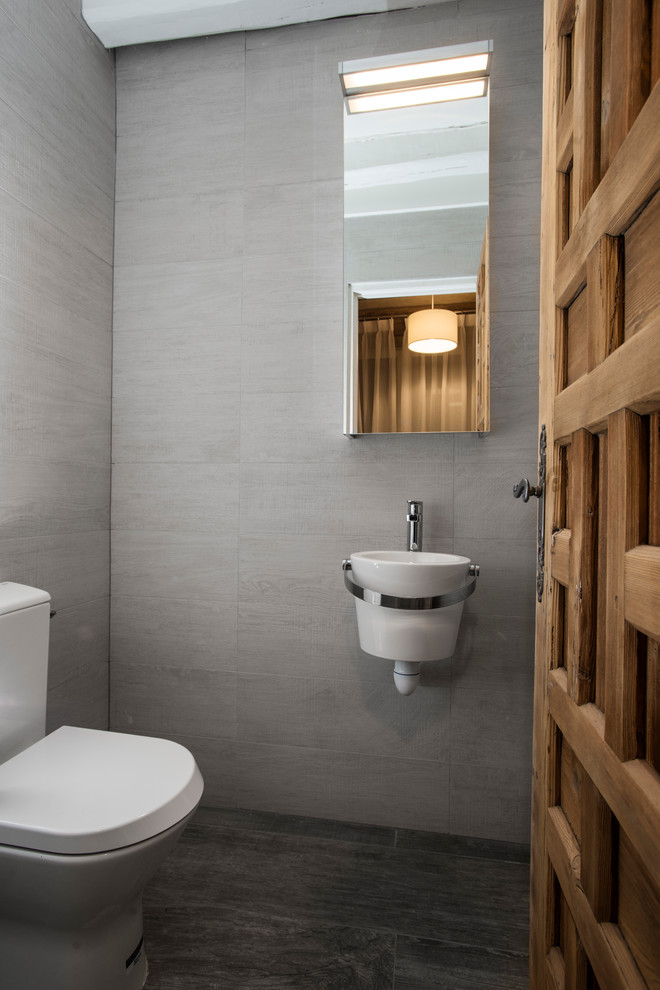 Idées déco pour un petit WC et toilettes contemporain avec WC à poser, un carrelage gris, des carreaux de céramique, un mur gris, un sol en carrelage de céramique et un lavabo suspendu.