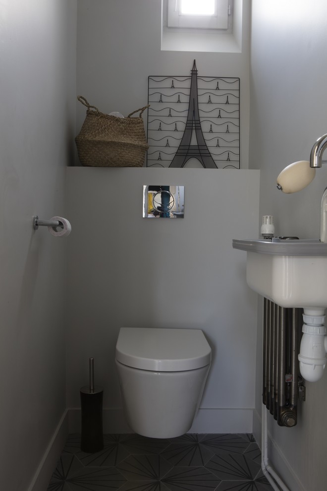パリにある低価格の中くらいなエクレクティックスタイルのおしゃれなトイレ・洗面所 (壁掛け式トイレ、白い壁、コンクリートの床、壁付け型シンク、グレーの床) の写真