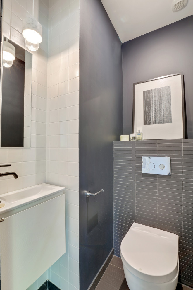 Exempel på ett mellanstort modernt toalett, med luckor med profilerade fronter, vita skåp, en vägghängd toalettstol, blå kakel, keramikplattor, vita väggar, klinkergolv i keramik, ett väggmonterat handfat, bänkskiva i akrylsten och svart golv