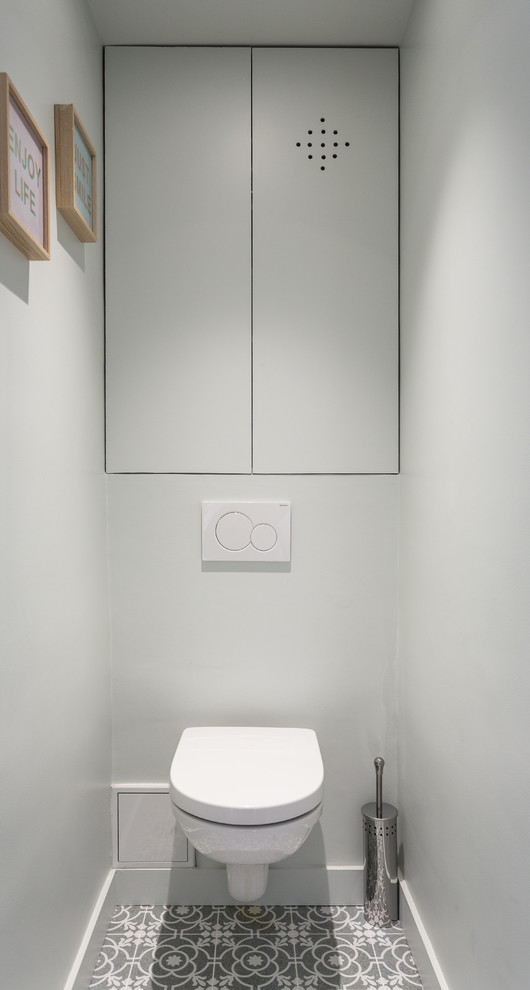 Immagine di un piccolo bagno di servizio moderno con ante a filo, ante grigie, WC sospeso, piastrelle grigie, pareti grigie, pavimento in cementine, pavimento grigio e top bianco