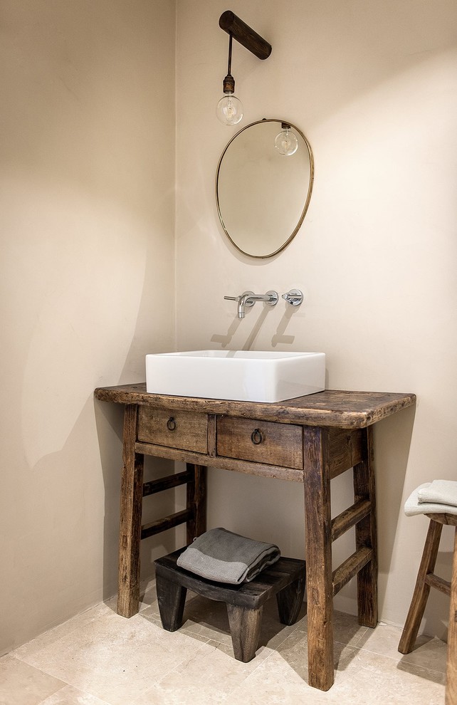 カターニア／パルレモにある小さな地中海スタイルのおしゃれなトイレ・洗面所 (ベージュのタイル、ベージュの壁、大理石の床、横長型シンク、木製洗面台、ベージュの床、ブラウンの洗面カウンター) の写真