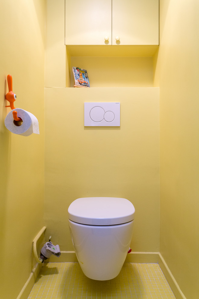 Inspiration for a small modern cloakroom in Other with flat-panel cabinets, yellow cabinets, a wall mounted toilet, yellow tiles, yellow walls, mosaic tile flooring, solid surface worktops, yellow floors and white worktops.