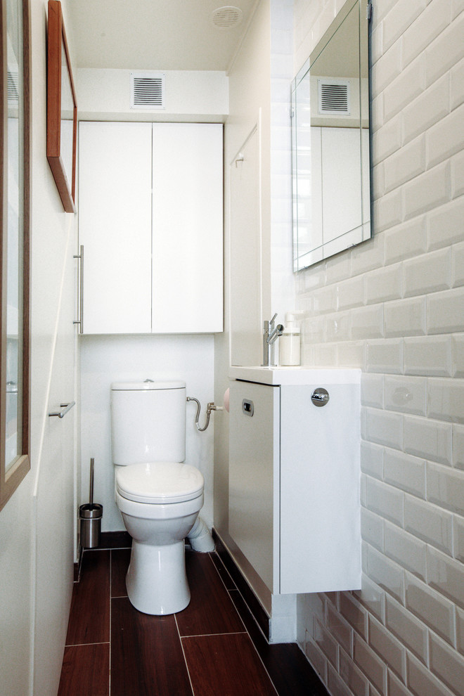 Design ideas for a small contemporary cloakroom in Paris with beaded cabinets, white cabinets, a one-piece toilet, white tiles, metro tiles, white walls, ceramic flooring, a wall-mounted sink, glass worktops, brown floors and white worktops.