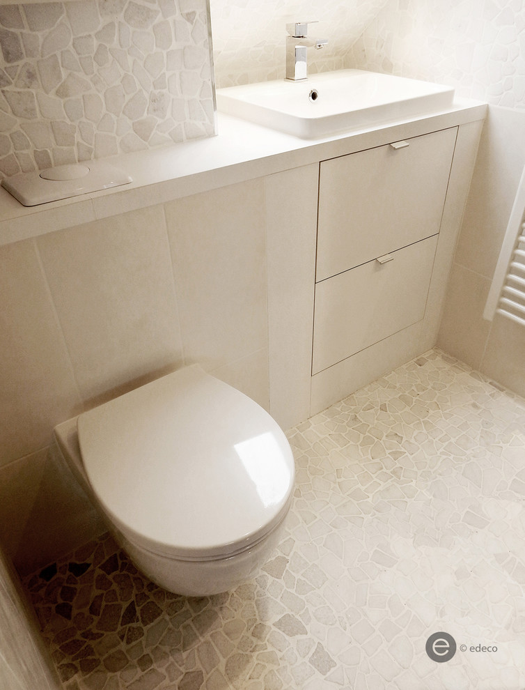 Small contemporary cloakroom in Paris with recessed-panel cabinets, white cabinets, a wall mounted toilet, white tiles, pebble tiles, white walls, pebble tile flooring, a submerged sink and laminate worktops.