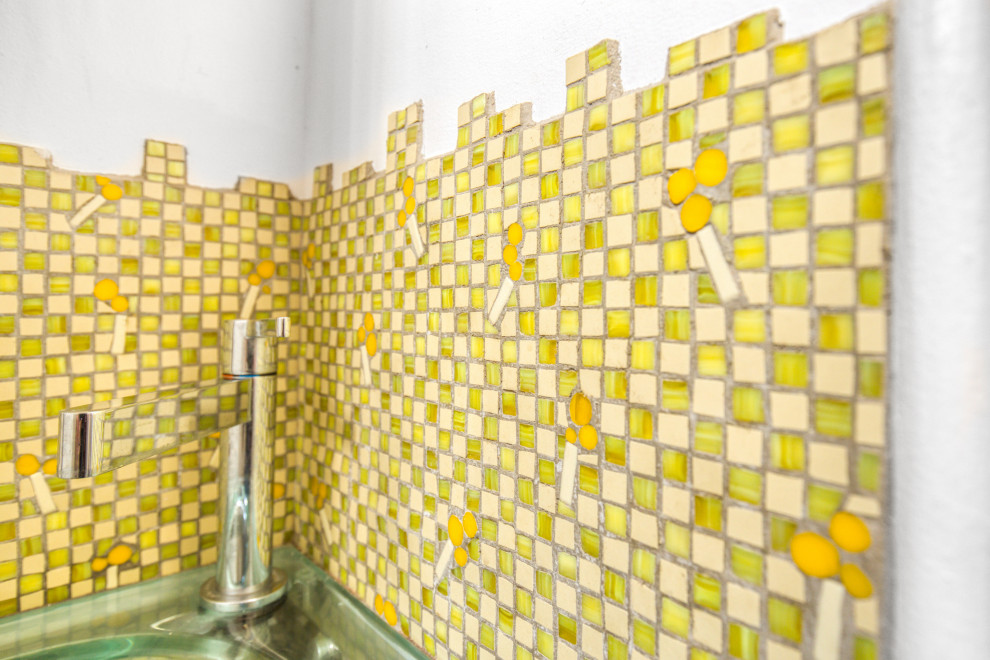 Amerikansk inredning av ett toalett, med gul kakel, mosaik, gula väggar och mosaikgolv