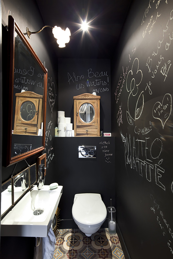 Immagine di un piccolo bagno di servizio minimal con WC sospeso, pareti nere, pavimento con piastrelle in ceramica e lavabo integrato