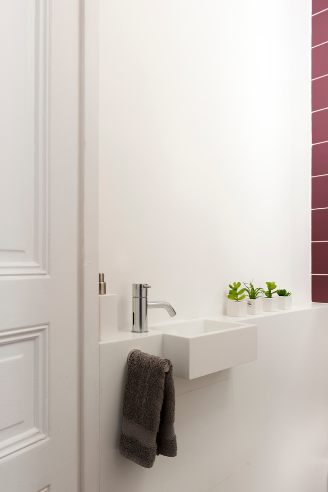 Inredning av ett modernt toalett, med keramikplattor, vita väggar och ett integrerad handfat