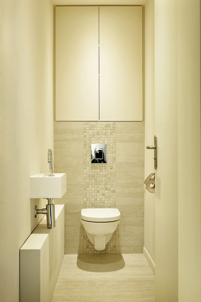 Immagine di un piccolo bagno di servizio moderno con ante a filo, ante beige, WC sospeso, piastrelle beige, piastrelle a mosaico, pareti beige, pavimento con piastrelle in ceramica, lavabo sospeso, top in superficie solida, pavimento beige e top bianco