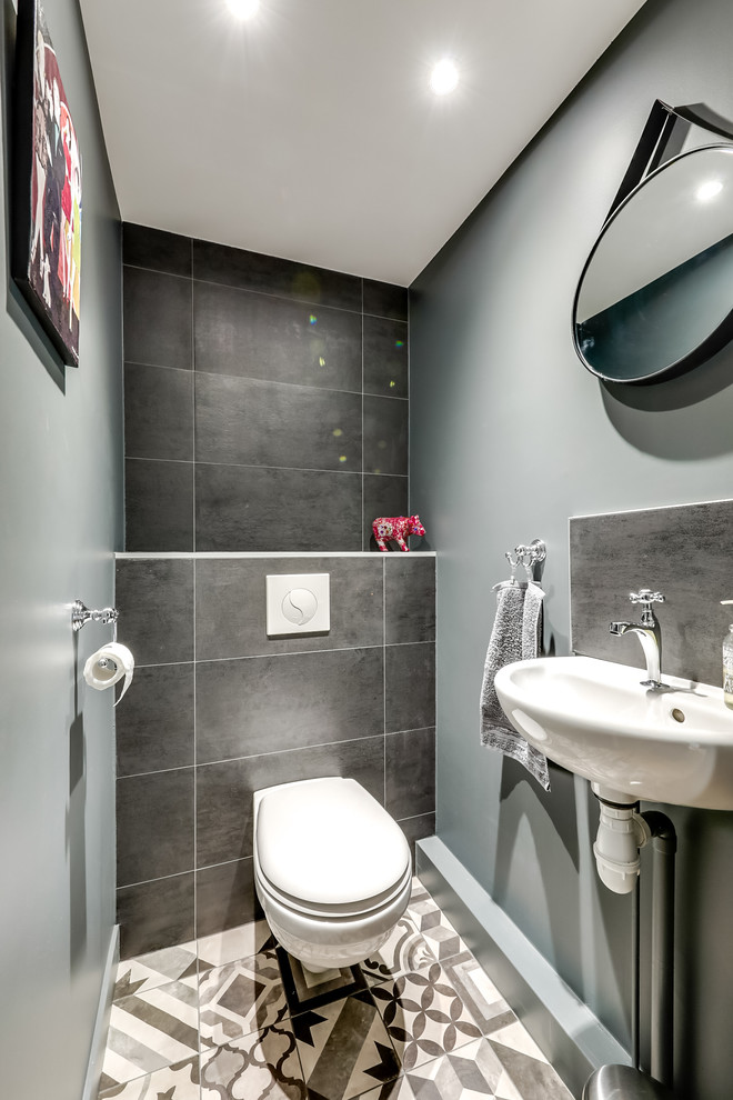 Inspiration för ett litet funkis toalett, med en vägghängd toalettstol, blå kakel, grå kakel, svart kakel, cementgolv, flerfärgat golv, ett väggmonterat handfat, grå väggar och kaklad bänkskiva