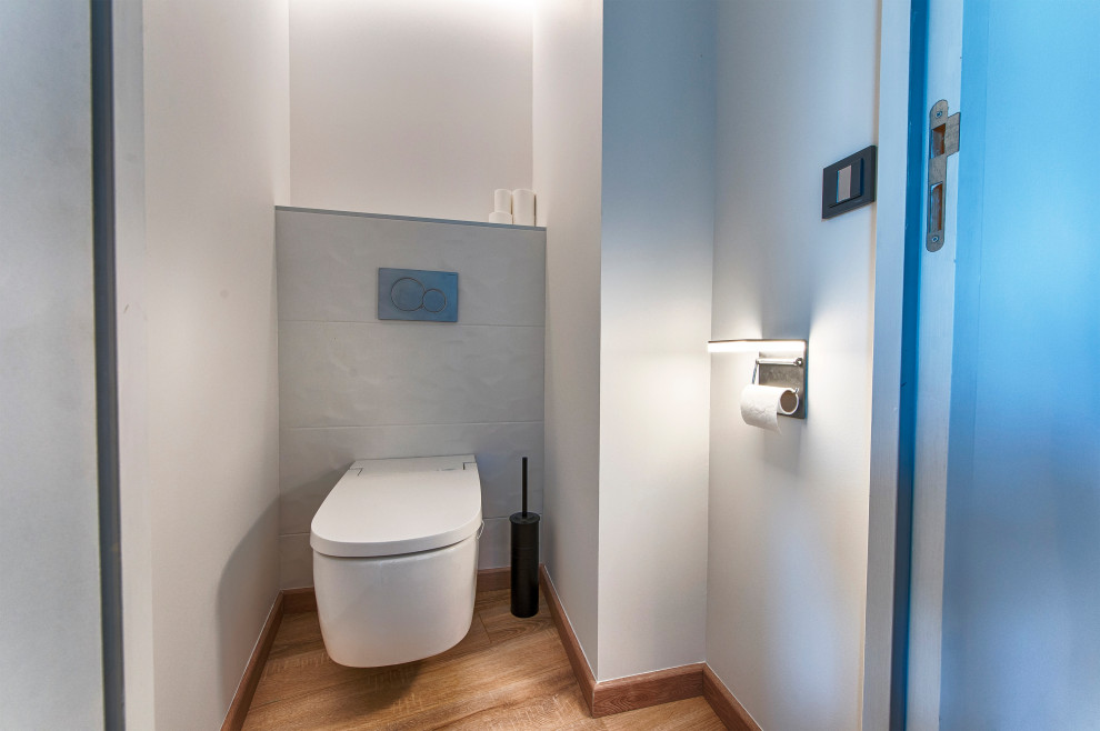 Idées déco pour un WC suspendu contemporain avec un carrelage blanc, des carreaux de céramique, un mur blanc, parquet clair et un sol beige.