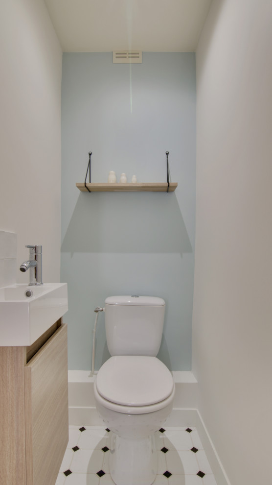 Kleine Skandinavische Gästetoilette mit Kassettenfronten, hellen Holzschränken, Toilette mit Aufsatzspülkasten, blauer Wandfarbe, Porzellan-Bodenfliesen, Einbauwaschbecken und weißem Boden in Paris