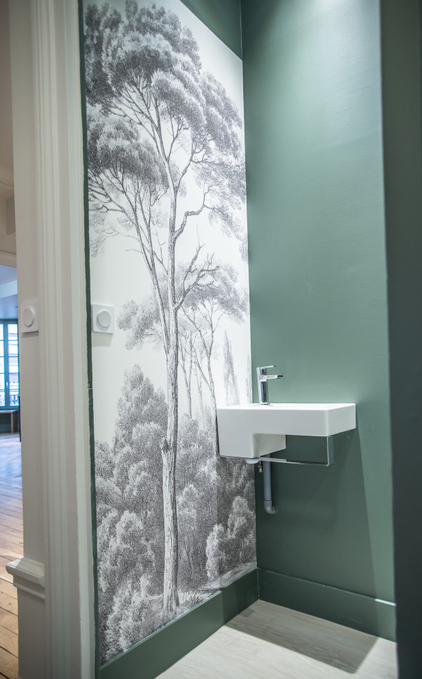 Cette image montre un WC suspendu traditionnel avec un mur vert, sol en stratifié, un lavabo suspendu et un plan de toilette blanc.