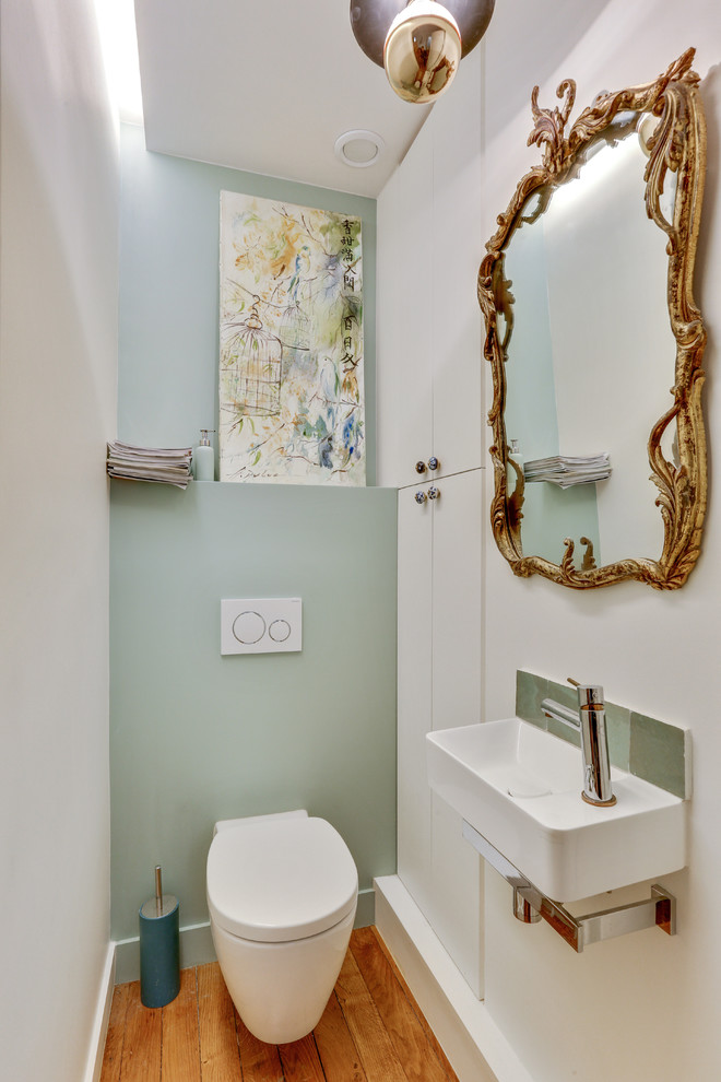 Foto di un bagno di servizio classico con WC sospeso, pareti verdi, pavimento in legno massello medio, lavabo sospeso e pavimento marrone