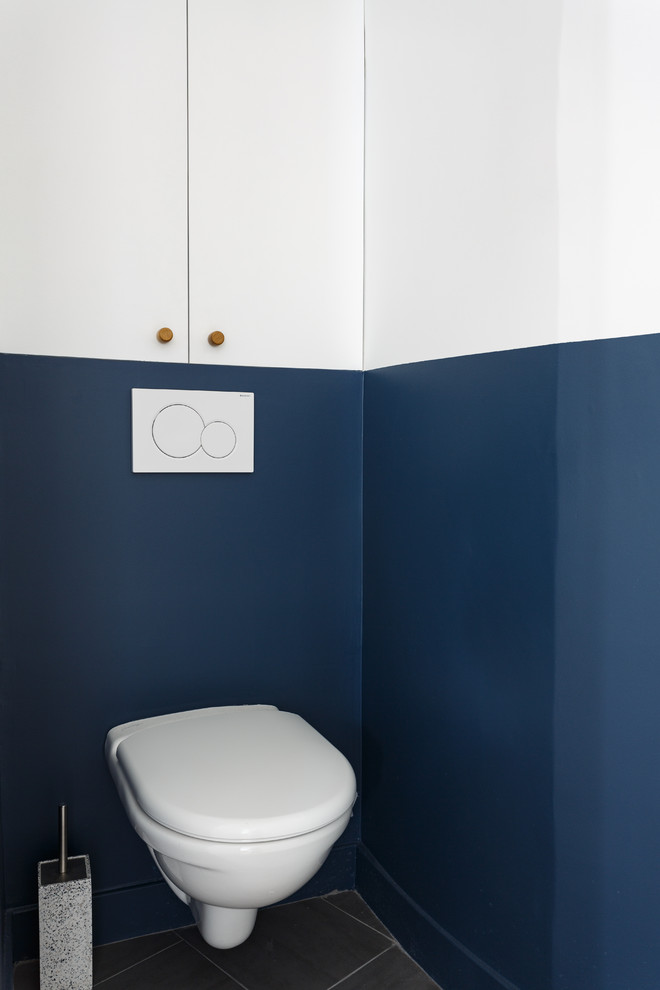 This is an example of a small scandi cloakroom in Paris with a wall mounted toilet, blue walls, ceramic flooring and black floors.