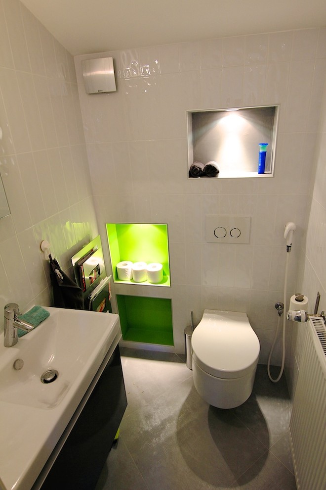 Идея дизайна: большой туалет в современном стиле с открытыми фасадами, зелеными фасадами, инсталляцией, белой плиткой, керамогранитной плиткой, белыми стенами, полом из керамической плитки и монолитной раковиной