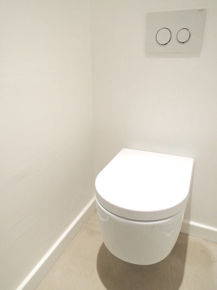 Aménagement d'un petit WC suspendu contemporain avec un carrelage beige, un mur blanc et sol en béton ciré.