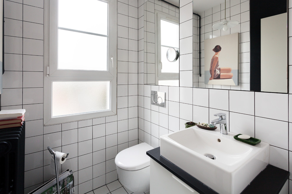 Стильный дизайн: большой туалет с инсталляцией, белой плиткой, подвесной раковиной и черной столешницей - последний тренд