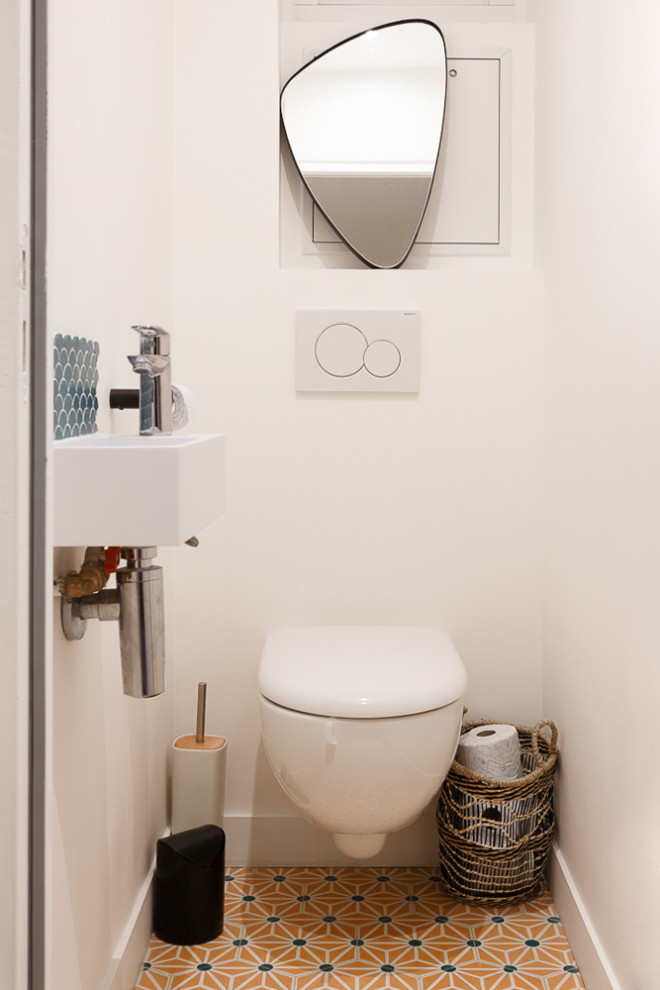 Exempel på ett litet modernt vit vitt toalett, med öppna hyllor, vita skåp, en vägghängd toalettstol, blå kakel, keramikplattor, vita väggar, cementgolv, ett väggmonterat handfat, bänkskiva i akrylsten och gult golv