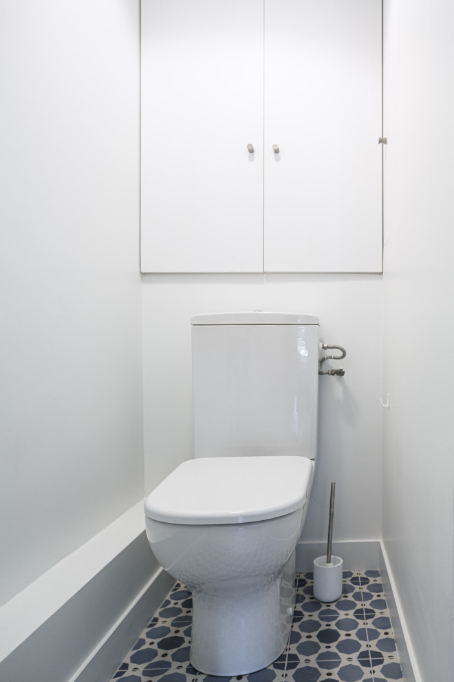 Photo of a small scandi cloakroom in Paris with beaded cabinets, white cabinets, a one-piece toilet, white tiles, white walls, cement flooring, solid surface worktops, blue floors, white worktops and a built in vanity unit.