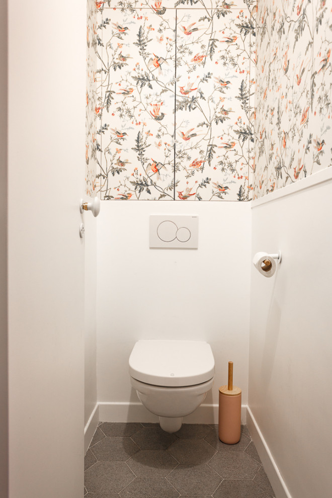 Kleine Moderne Gästetoilette mit Lamellenschränken, grünen Schränken, Wandtoilette, weißer Wandfarbe, Zementfliesen für Boden, grauem Boden, weißer Waschtischplatte, eingebautem Waschtisch und Tapetenwänden in Paris