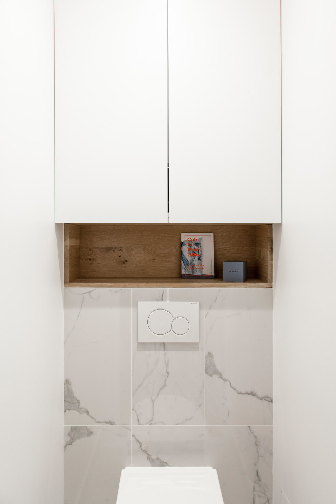 Réalisation d'un petit WC suspendu tradition avec des portes de placard blanches, un carrelage blanc, des carreaux de céramique, un sol en marbre et un plan de toilette en marbre.