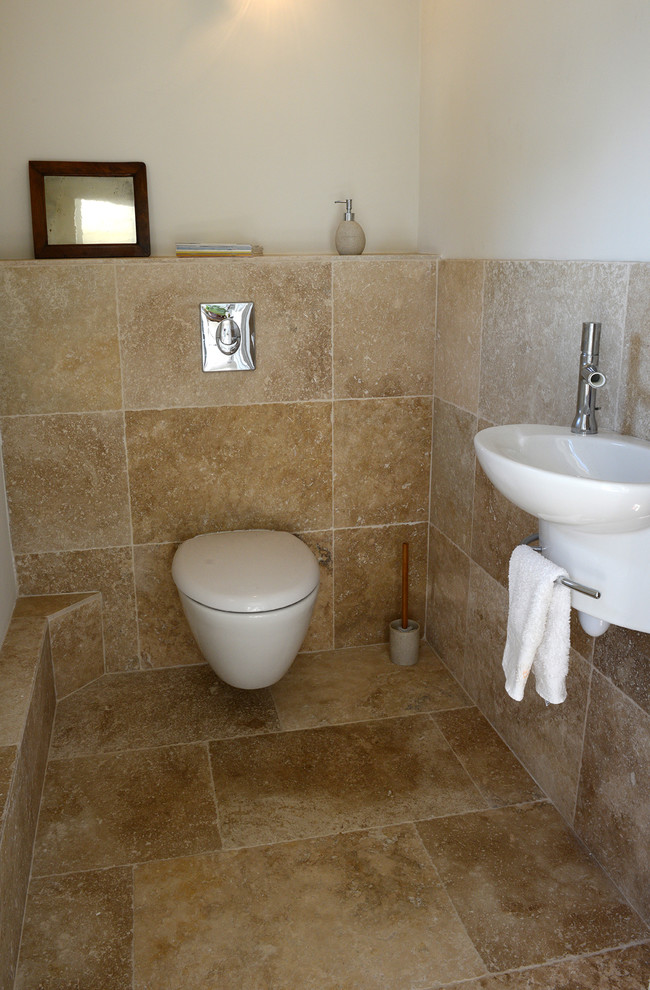 Idéer för mellanstora eklektiska vitt toaletter, med en vägghängd toalettstol, beige kakel, travertinkakel, vita väggar, travertin golv, ett väggmonterat handfat, bänkskiva i travertin och beiget golv