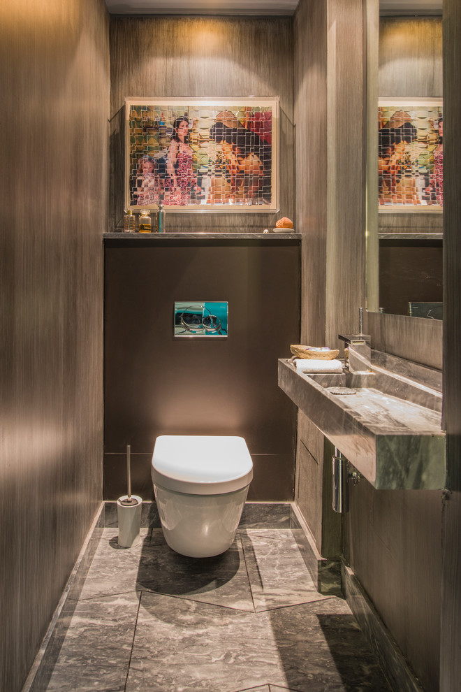 パリにあるラグジュアリーな広いコンテンポラリースタイルのおしゃれなトイレ・洗面所 (横長型シンク、グレーのタイル、グレーの壁、壁掛け式トイレ、大理石の床、大理石の洗面台) の写真