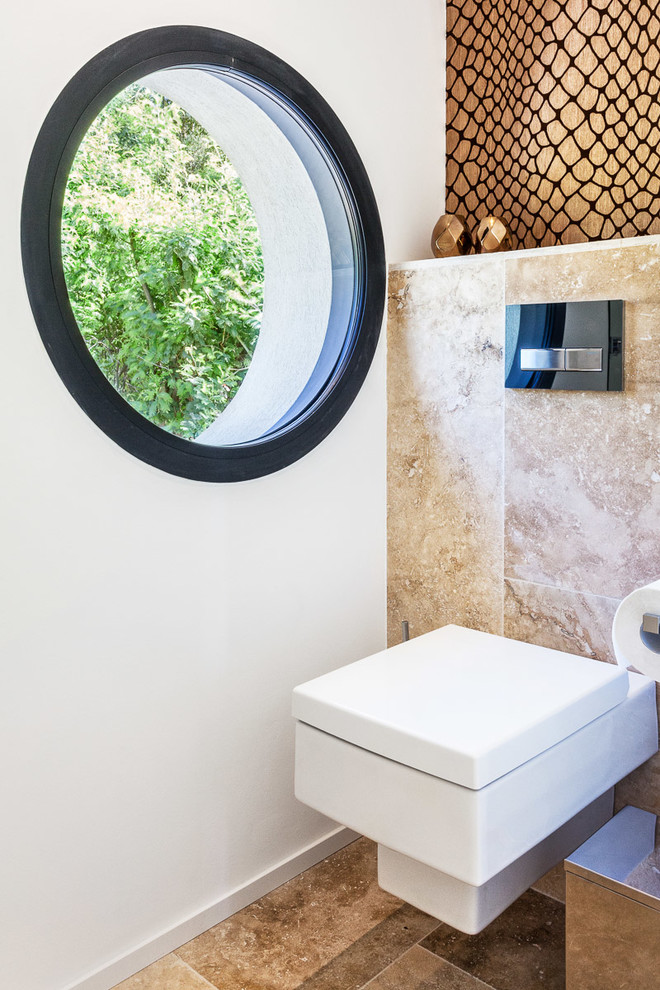 Bild på ett mellanstort funkis toalett, med en vägghängd toalettstol, stenkakel, vita väggar och beiget golv