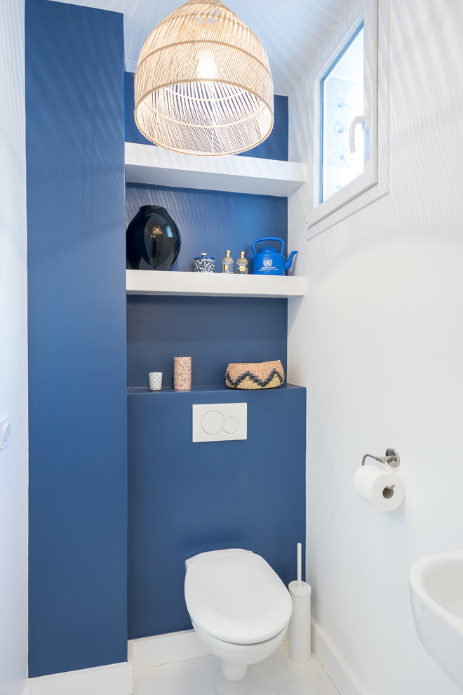 На фото: туалет среднего размера в стиле фьюжн с инсталляцией, синими стенами и подвесной раковиной с