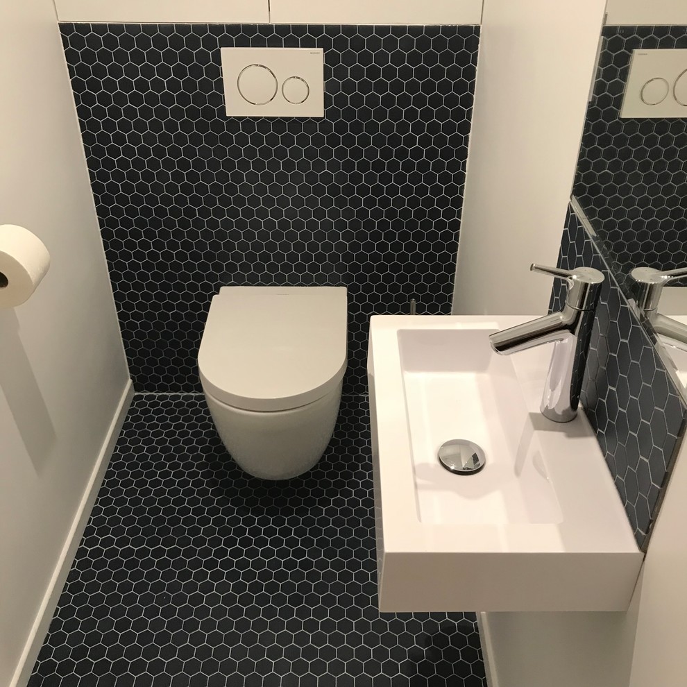 Cette image montre un WC suspendu design de taille moyenne avec un placard à porte affleurante, des portes de placard blanches, un carrelage bleu, des carreaux en terre cuite, un mur blanc, tomettes au sol, un lavabo suspendu, un plan de toilette en quartz modifié et un sol bleu.