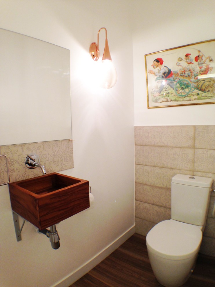 Aménagement d'un petit WC et toilettes bord de mer avec un carrelage beige, des carreaux de céramique, un mur blanc, un sol en linoléum, un lavabo suspendu, un plan de toilette en bois et un sol marron.