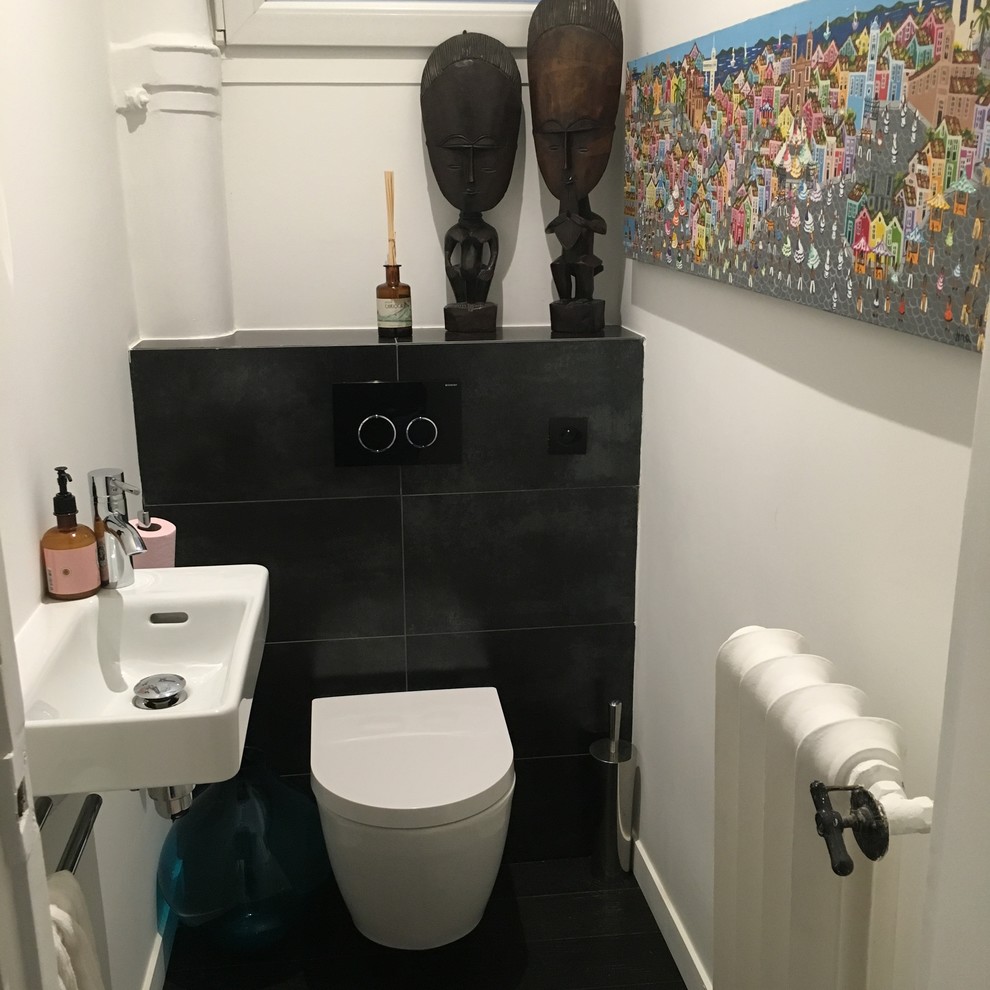 Esempio di un piccolo bagno di servizio con WC sospeso, lastra di pietra, pareti bianche, parquet scuro, lavabo sospeso e pavimento nero