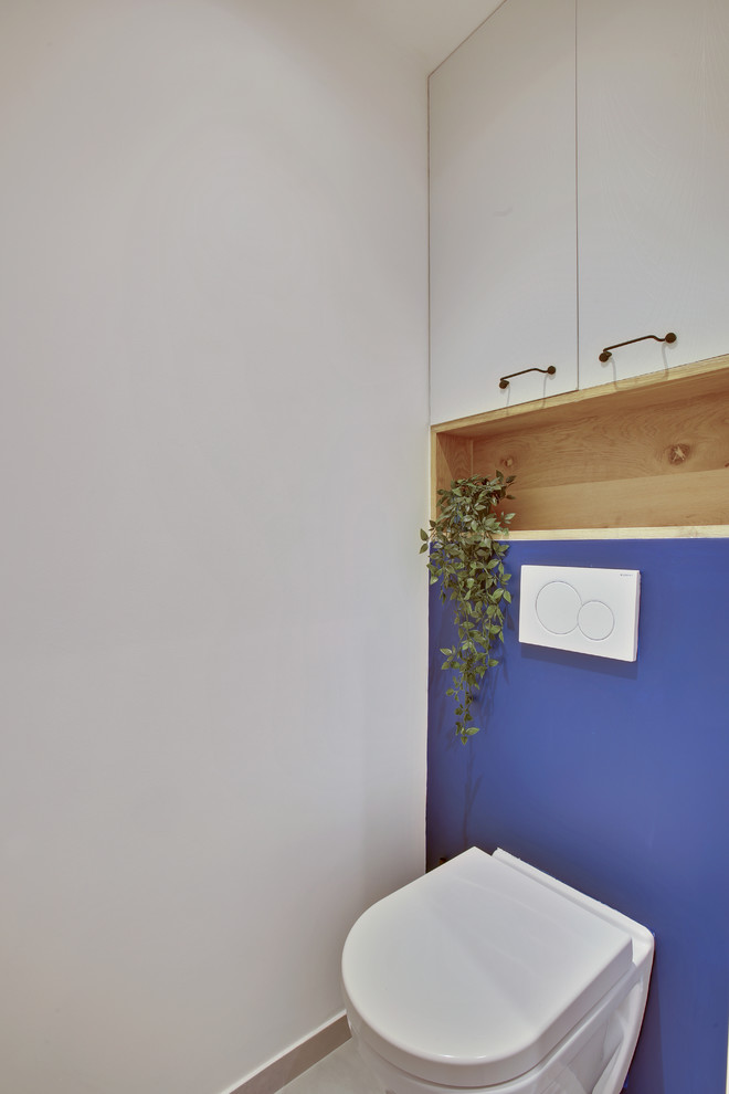 Aménagement d'un petit WC suspendu éclectique avec un placard à porte affleurante, des portes de placard blanches, un carrelage blanc, des carreaux de céramique, un mur bleu, sol en béton ciré et un sol gris.