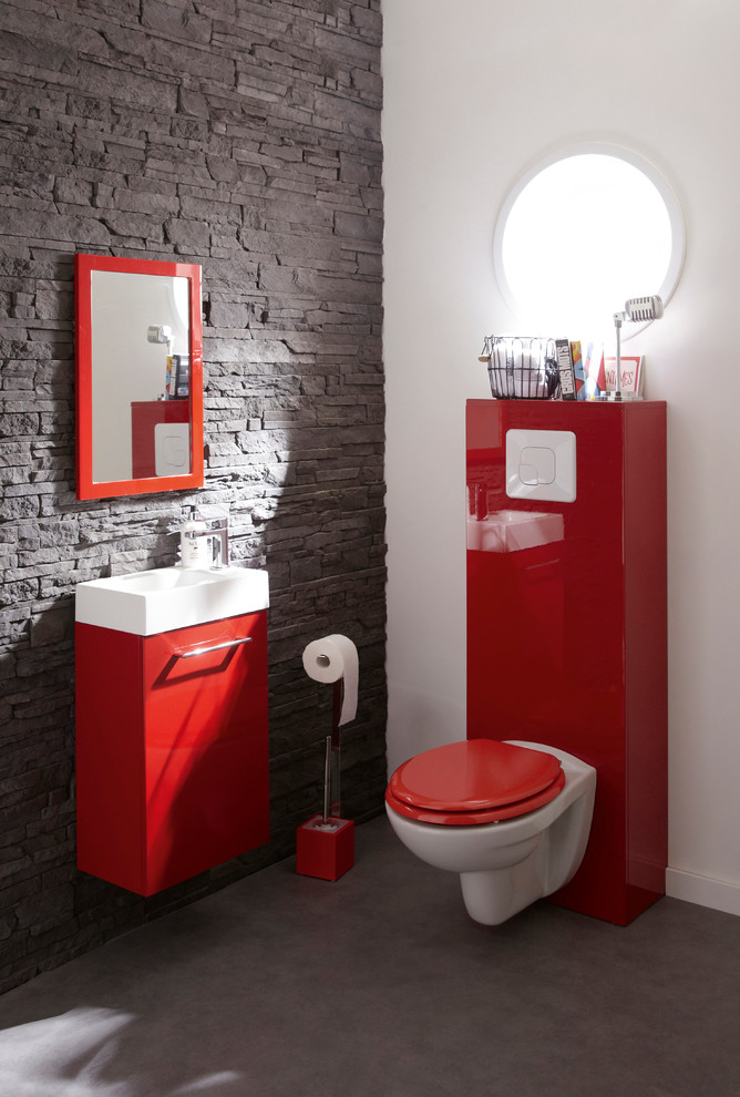 Bild på ett mellanstort funkis toalett, med en vägghängd toalettstol, ett väggmonterat handfat och grå väggar