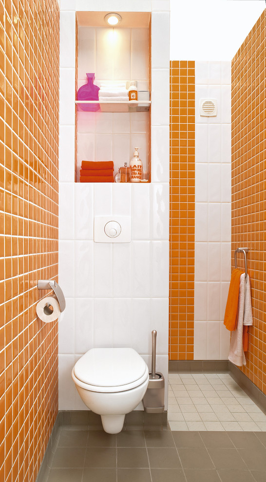 На фото: туалет среднего размера в стиле модернизм с инсталляцией и оранжевыми стенами