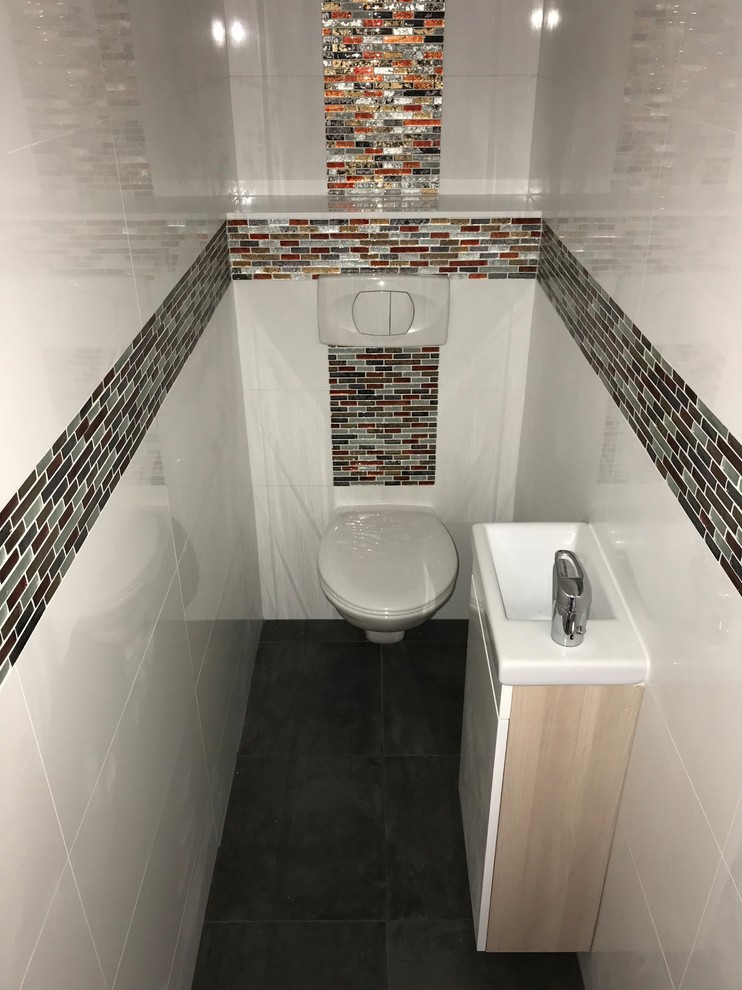 Inspiration for a medium sized modern cloakroom in Paris with beaded cabinets, light wood cabinets, a wall mounted toilet, multi-coloured tiles, porcelain tiles, white walls, ceramic flooring, a wall-mounted sink, tiled worktops, grey floors and multi-coloured worktops.