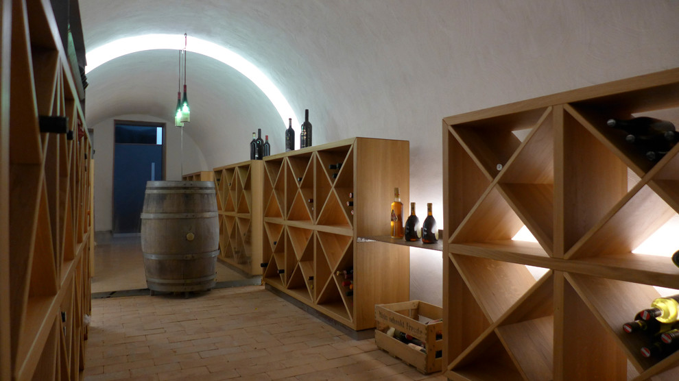 Large rustic wine cellar in Frankfurt with brick flooring, storage racks and orange floors.
