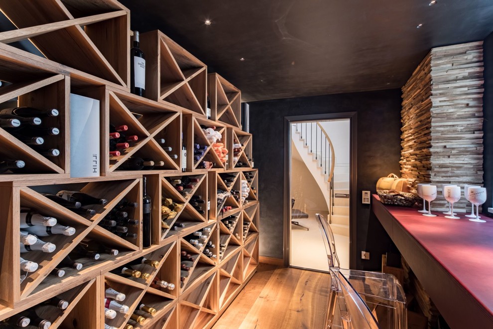 Aménagement d'une cave à vin contemporaine de taille moyenne avec un sol en bois brun, des casiers losange et un sol marron.
