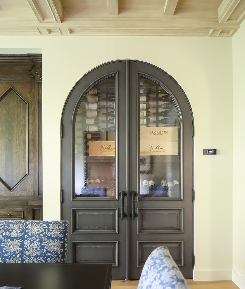 Photo of a small mediterranean wine cellar in Los Angeles with light hardwood flooring, storage racks and beige floors.