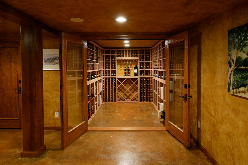 Réalisation d'une grande cave à vin tradition avec sol en béton ciré et des casiers.