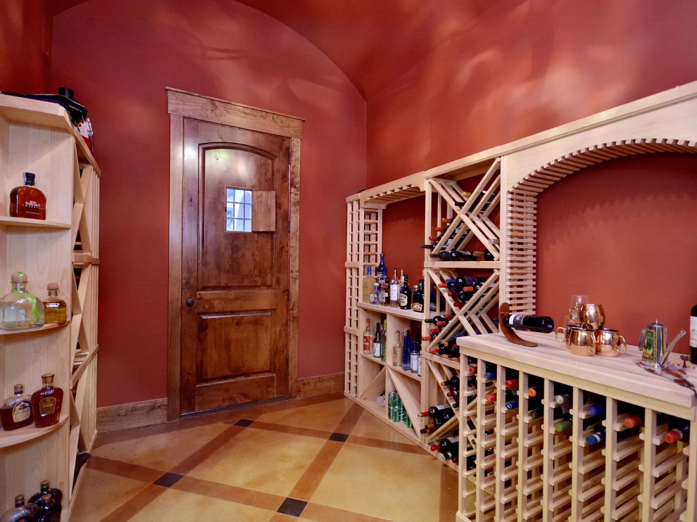 Aménagement d'une très grande cave à vin méditerranéenne avec sol en béton ciré, des casiers et un sol multicolore.